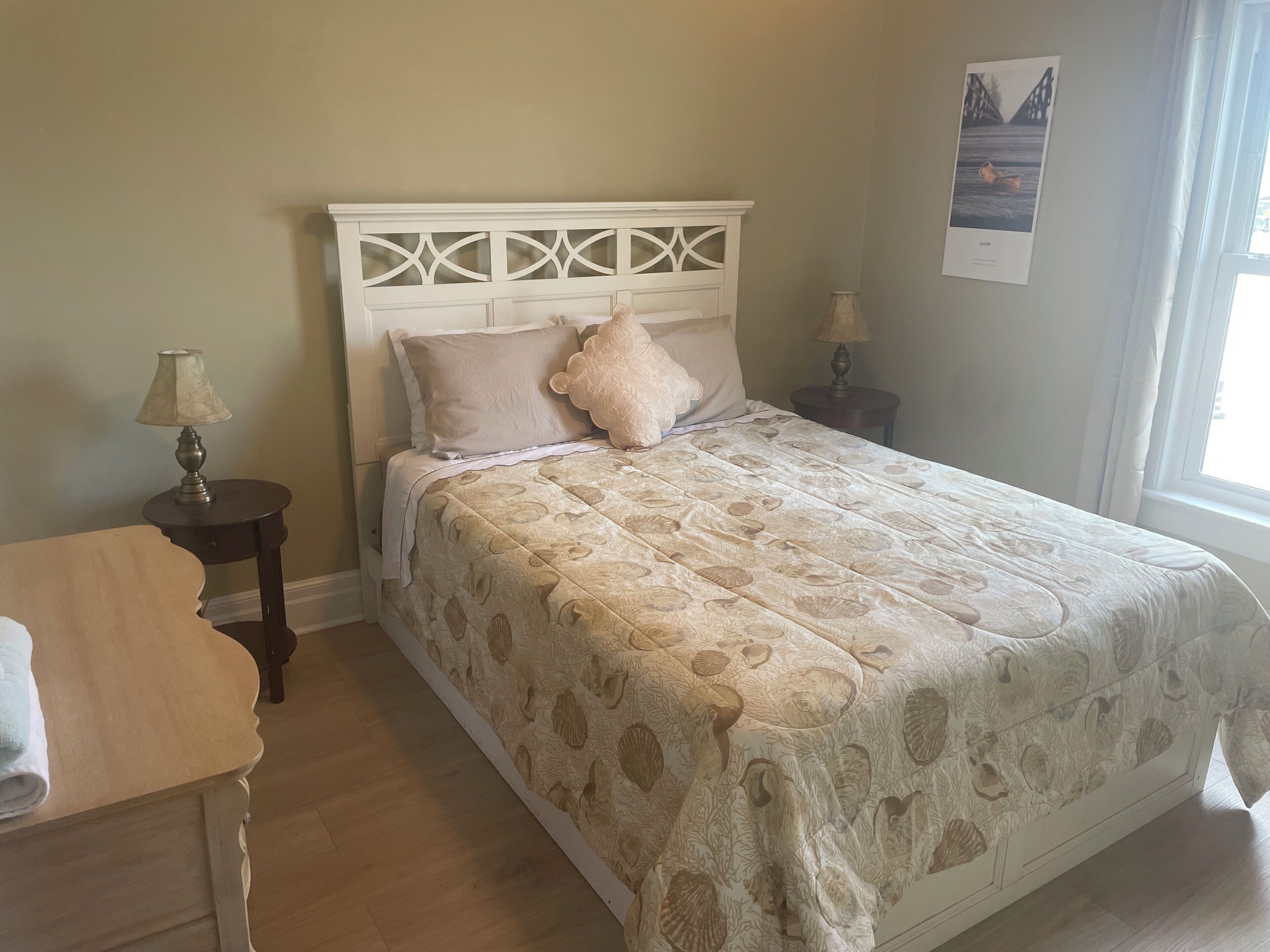 A bedroom with a bed, a nightstand, a lamp, and a window.