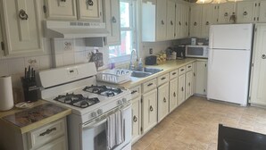 A kitchen with white cabinets, a gas stove, a microwave, and a refrigerator. - Ultra Close to the Falls (Niagara Falls)
