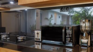 A modern kitchen with a black microwave, a toaster, and a blender on a glossy countertop. - Famiglie Guest House (Munggu)
