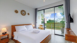 A modern hotel room with a large bed, a TV, and a balcony with a view of the outdoors. - Famiglie Guest House (Munggu)