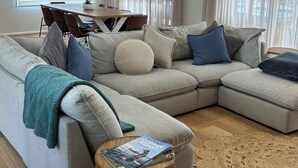 A modern living room with a sectional sofa, a small round table, and a dining area with a table and chairs.