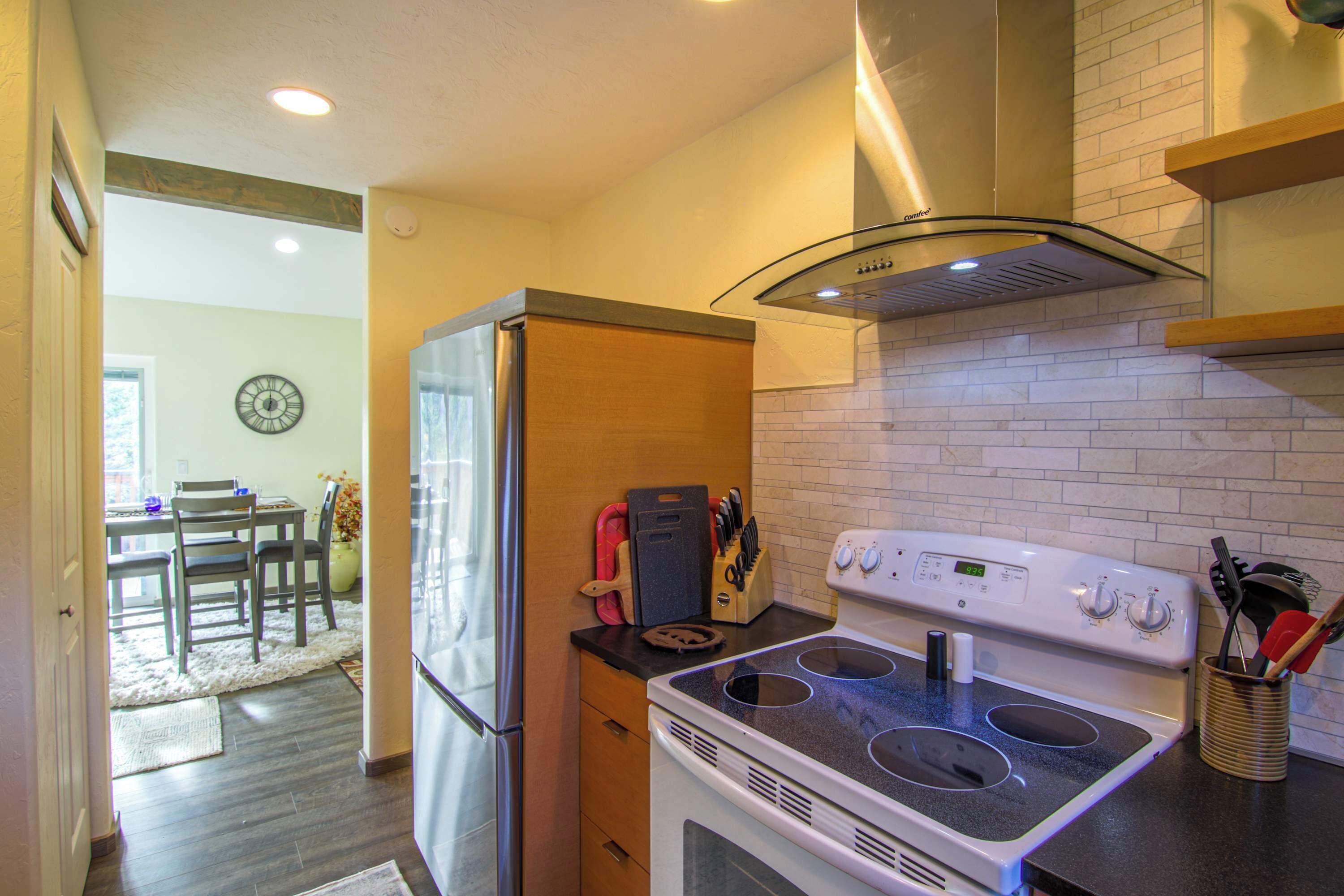 A kitchen with a white stove, a refrigerator, and a dining area with a table and chairs.