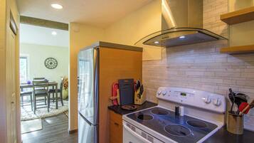 A kitchen with a white stove, a refrigerator, and a dining area with a table and chairs.