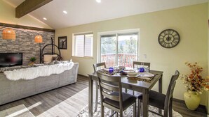 A dining area with a table set for four, a sofa, and a TV in the background.