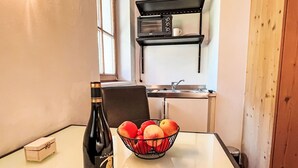 Een keuken met een wit aanrecht, een wijnfles en een schaal met fruit.