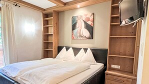 A bedroom with a bed, a painting, a TV, and built-in shelving. - Apartment Studio by Interhome (Oberndorf in Tirol)