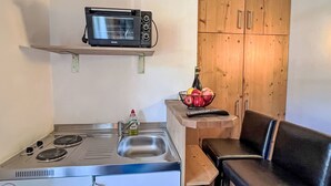 A compact kitchenette with a microwave, stove, and sink.