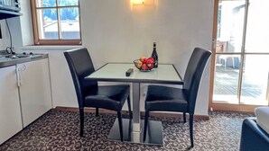 A small kitchen with a dining table and chairs, a microwave, and a fruit bowl. - Cheeky Apartment by Interhome (Oberndorf in Tirol)