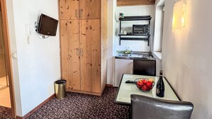 A compact kitchen with wooden cabinets, a microwave, and a small dining area with a table and chair. - Cheeky Apartment by Interhome (Oberndorf in Tirol)