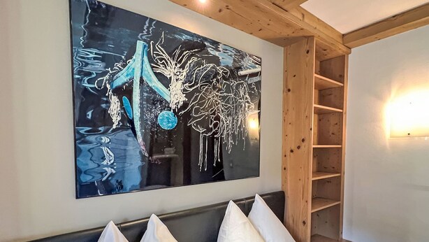 A hotel room with a large abstract painting on the wall, a wooden headboard, and a built-in shelf unit. - Cheeky Apartment by Interhome (Oberndorf in Tirol)