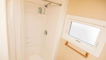 A bathroom with a shower, a window, and a towel rack.