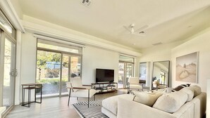 Ein modernes Wohnzimmer mit Sofa, Fernseher und großem Fenster.