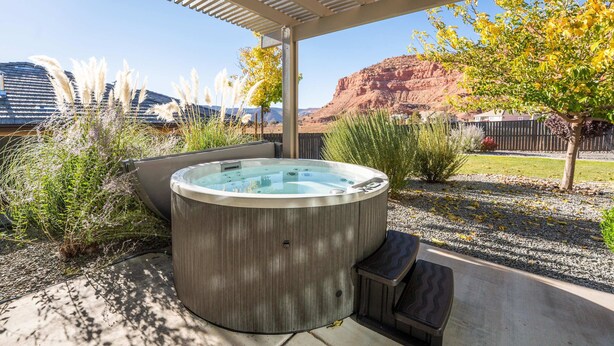 Ein Whirlpool in einer überdachten Außenbereich mit Blick auf einen Berg und ein Haus im Hintergrund.