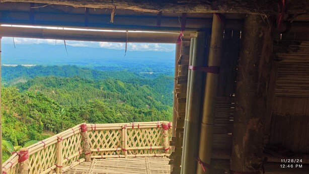 A bamboo-framed balcony with a view of a lush green landscape. - Mirinja Valley Megh Machang Resort (Lama)