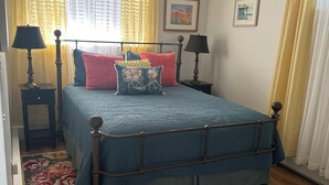 Ein Schlafzimmer mit einem Bett, zwei Nachttischen, einem Deckenventilator und einem Blumenteppich.