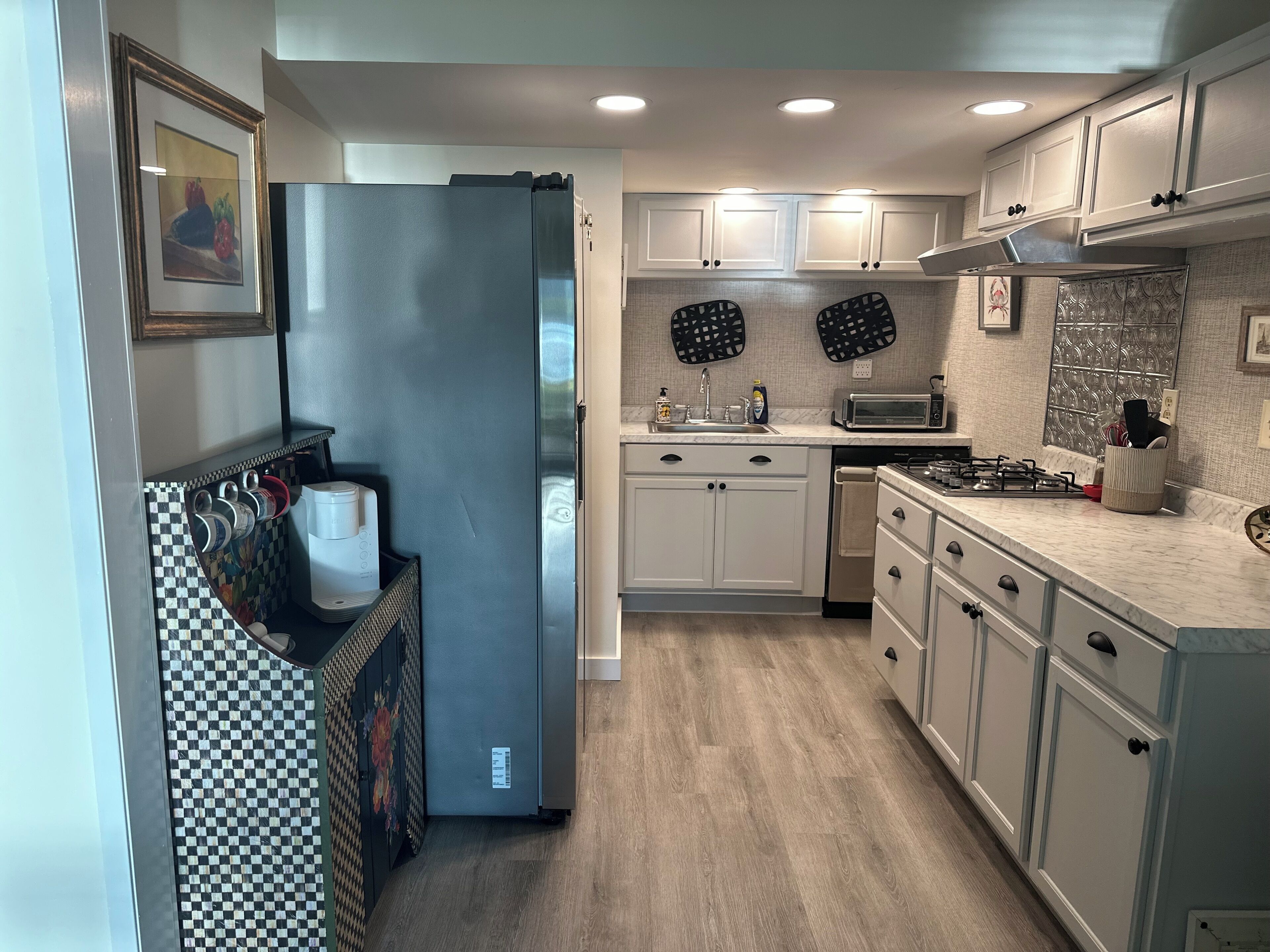 A modern kitchen with white cabinets, a refrigerator, a microwave, and a sink.