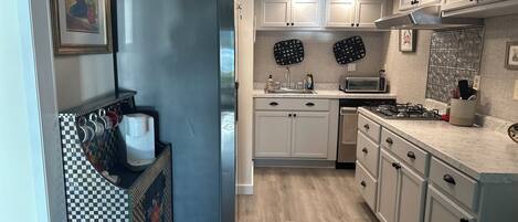 A modern kitchen with white cabinets, a refrigerator, a microwave, and a sink.