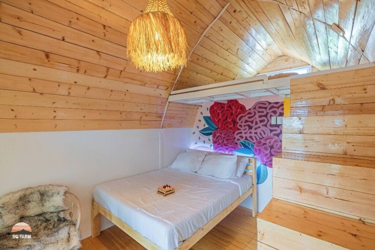 Un dormitorio de cabaña de madera con una cama, una lámpara colgante y un mural en la pared.