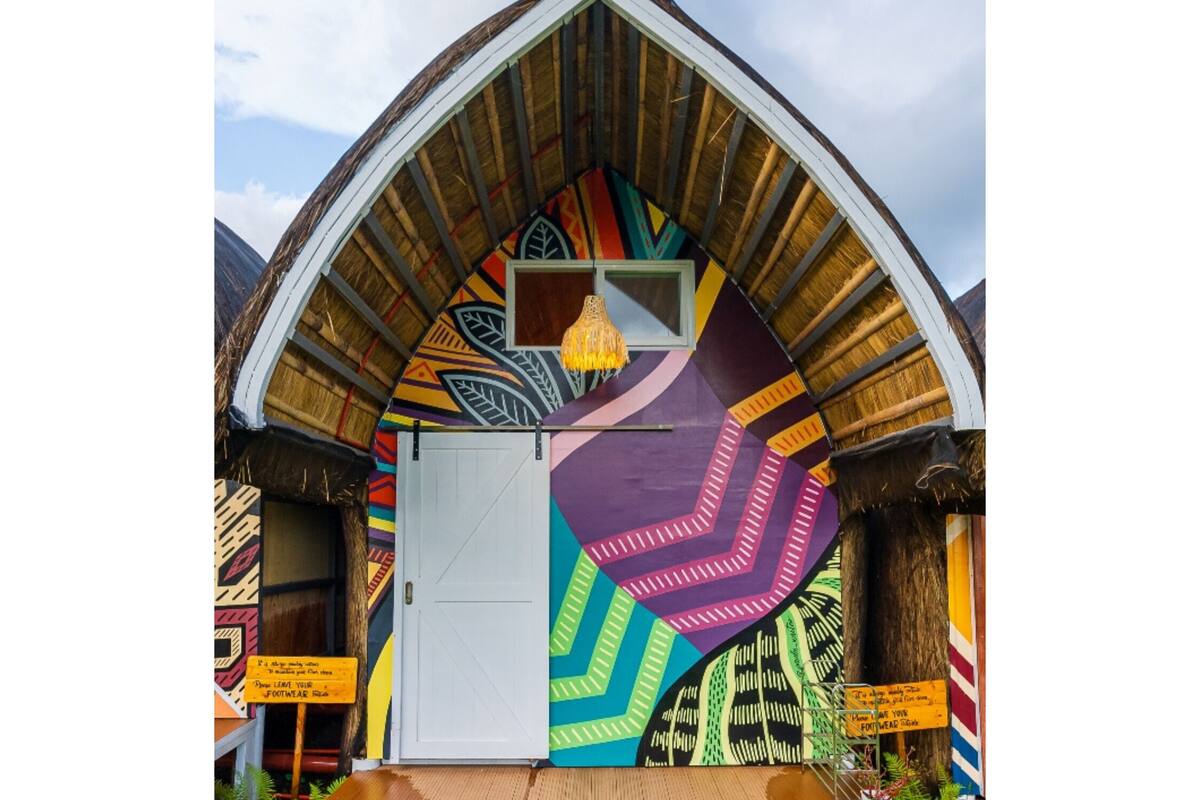 Un edificio colorido con una puerta blanca y un mural llamativo.