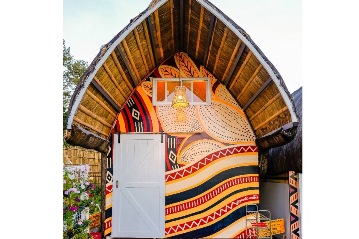 Un pequeño edificio colorido con techo de paja y puerta blanca.