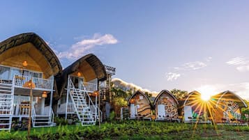 Una hilera de cabañas con techos curvos y diseños únicos, con zonas de estar al aire libre, rodeadas de abundante vegetación.