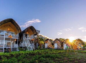 A row of unique, curved-roofed cabins with outdoor seating areas, surrounded by lush greenery. - Strawberry Guyabano Farm (Tupi)