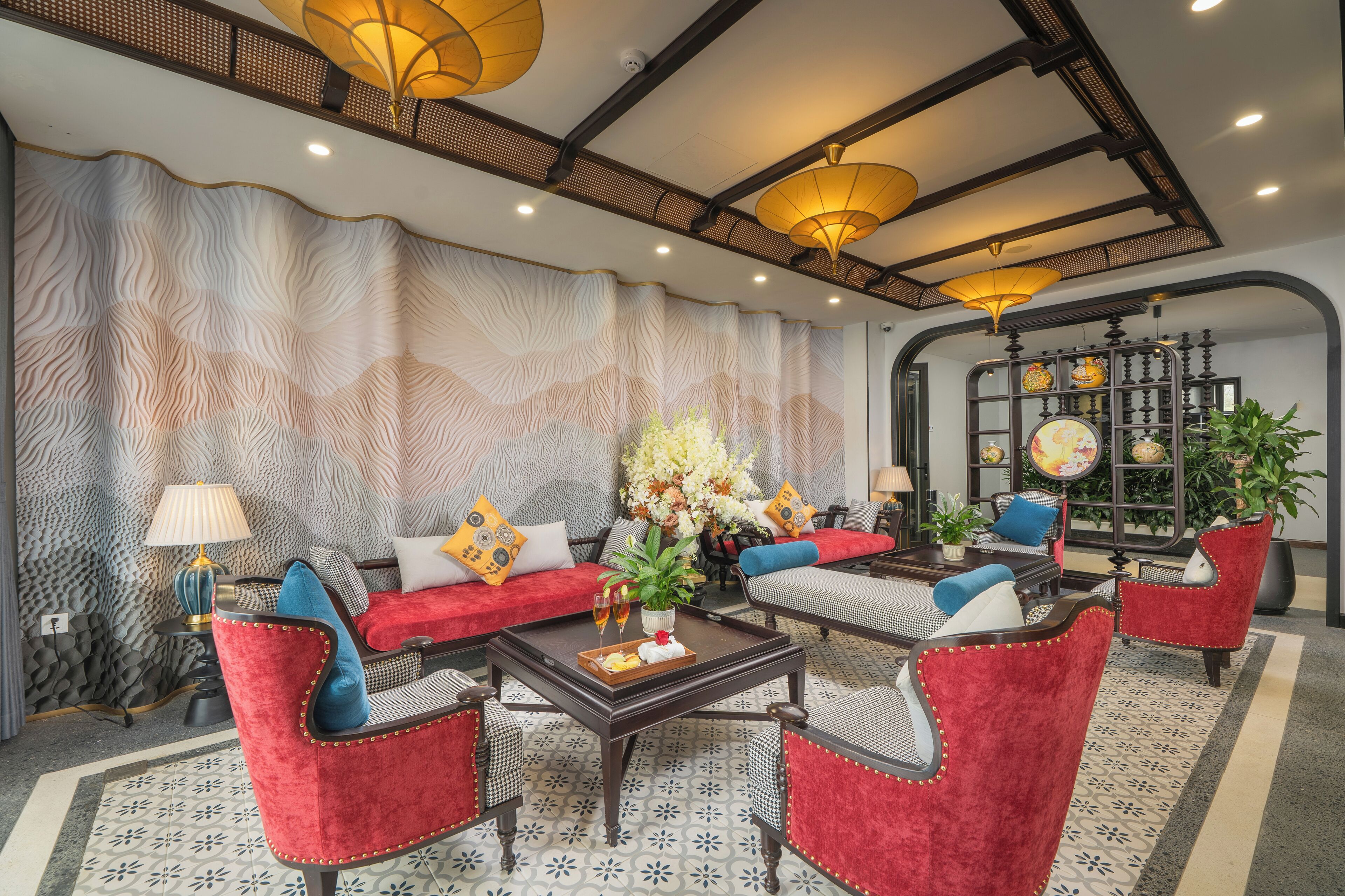 Um lounge moderno com sofás estofados vermelhos, uma mesa de centro e luminárias decorativas.