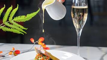 A hand pouring a liquid into a glass of champagne.