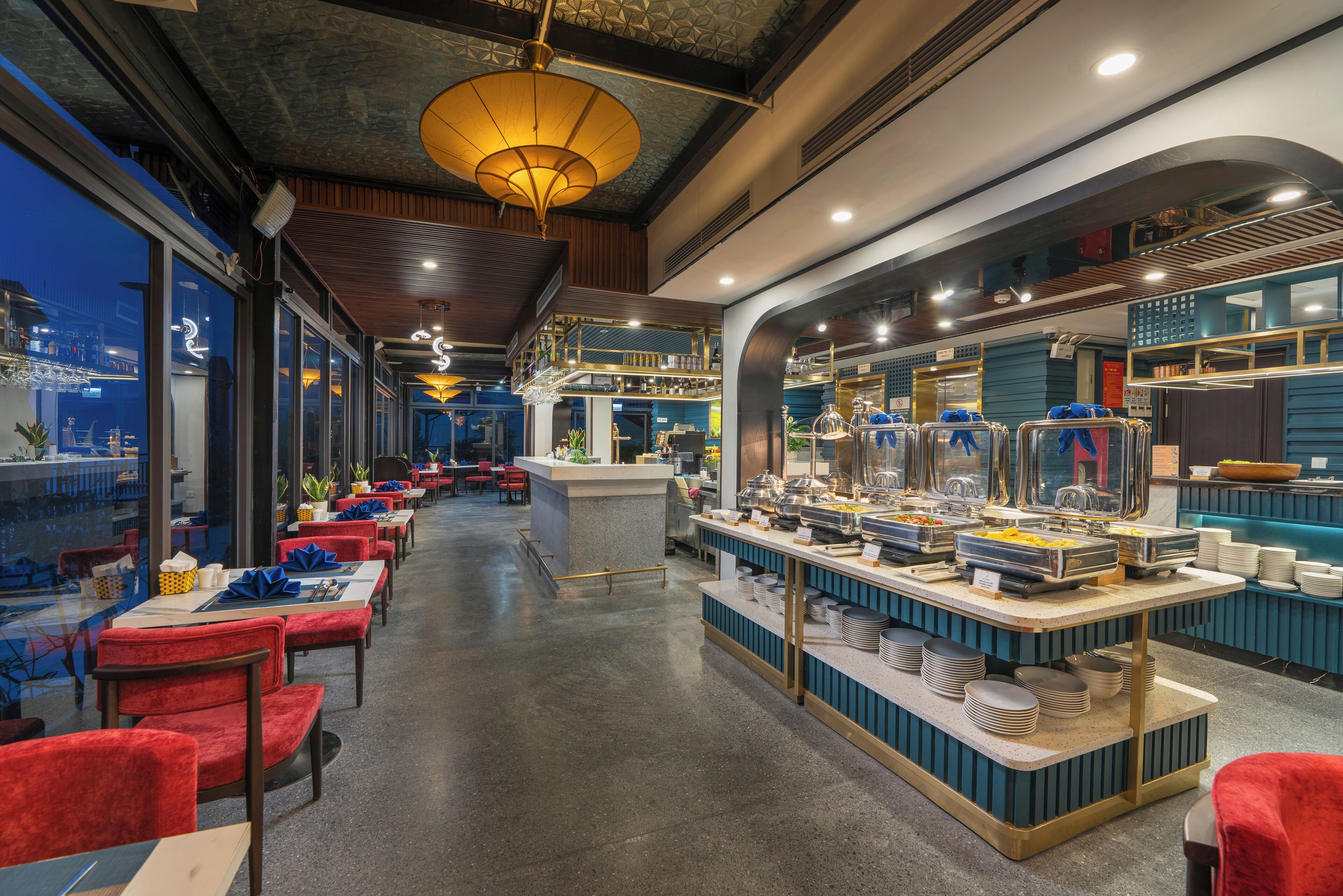 Un restaurante con mesas de buffet, sillas tapizadas en rojo y una barra con diferentes opciones de comida.