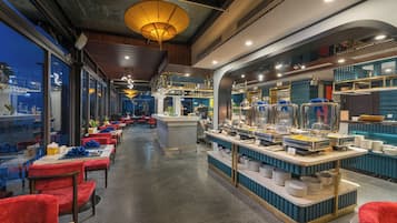 Un restaurante con mesas de buffet, sillas tapizadas en rojo y una barra con diferentes opciones de comida.