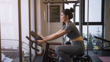 Ein Fitnessstudio mit einem Ergometer, Kraftgeräten und einem großen Fenster.