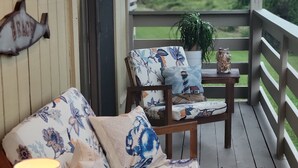 A wooden deck with a sofa and armchair, a lamp, and a potted plant. - Family Beach Retreat with Ocean Views and Pools (Tybee Island)