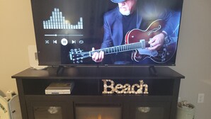 A television on a wooden entertainment center with a fireplace below. - Family Beach Retreat with Ocean Views and Pools (Tybee Island)