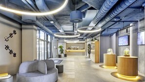 A modern interior with a reception desk, seating area, and a large window. - Sunday Düsseldorf Seestern (Dusseldorf)