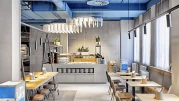 Una cafetería moderna con mostrador central, zona de estar y amplios ventanales.