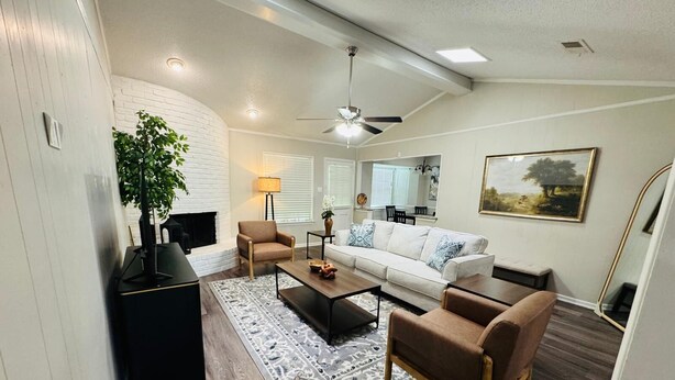 A modern living room with a fireplace, a sofa, a coffee table, and a TV.