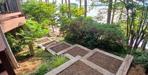 A garden with raised beds, a wooden deck, and a view of a body of water.
