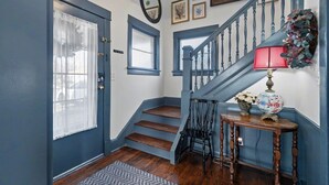 Un escalier avec des rampes bleues, un plancher en bois et une lampe posée sur une table.