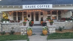 Un bâtiment sur lequel on peut lire l’inscription « CAUSE COFFEE » et qui possède un porche orné de plantes en pot.