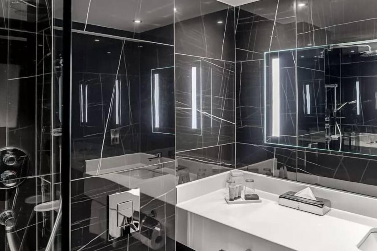 A modern bathroom with a glass partition, a white countertop, and a large mirror.