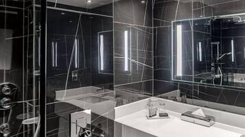A modern bathroom with a glass partition, a white countertop, and a large mirror.