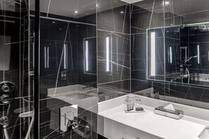 A modern bathroom with a glass partition, a white countertop, and a large mirror. - Sofitel London Gatwick (Horley)