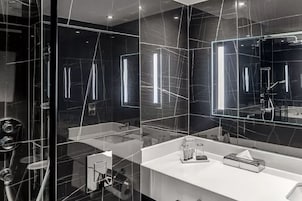 A modern bathroom with a glass partition, a white countertop, and a large mirror.