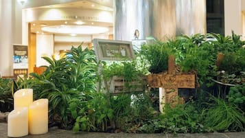 A reception area with a plant display, a sign, and a pillar.
