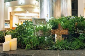 A reception area with a plant display, a sign, and a pillar. - Sofitel London Gatwick (Horley)
