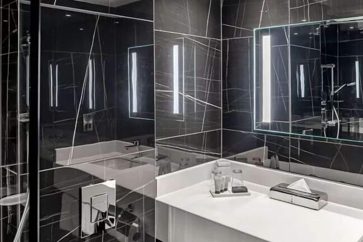 A modern bathroom with a glass shower enclosure, a white vanity, and a large mirror.