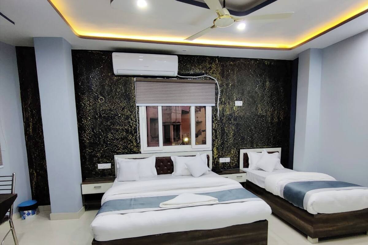 A modern hotel room with a large bed, a smaller bed, a desk, and a ceiling fan.