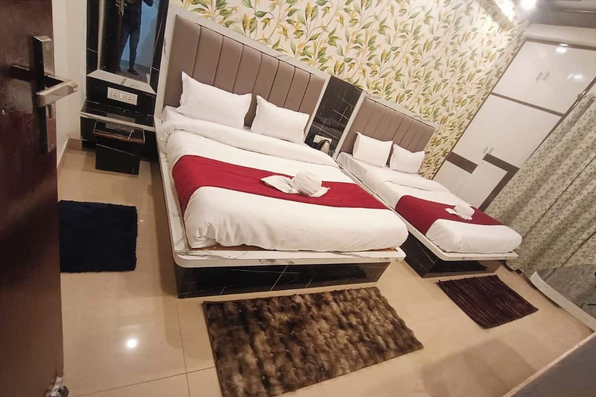 A hotel room with two beds, a large mirror, a wardrobe, and a small table.