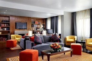 A modern living room with a sofa, armchairs, a coffee table, and a bookshelf. - Sheraton Grand Hotel & Spa (Edinburgh)