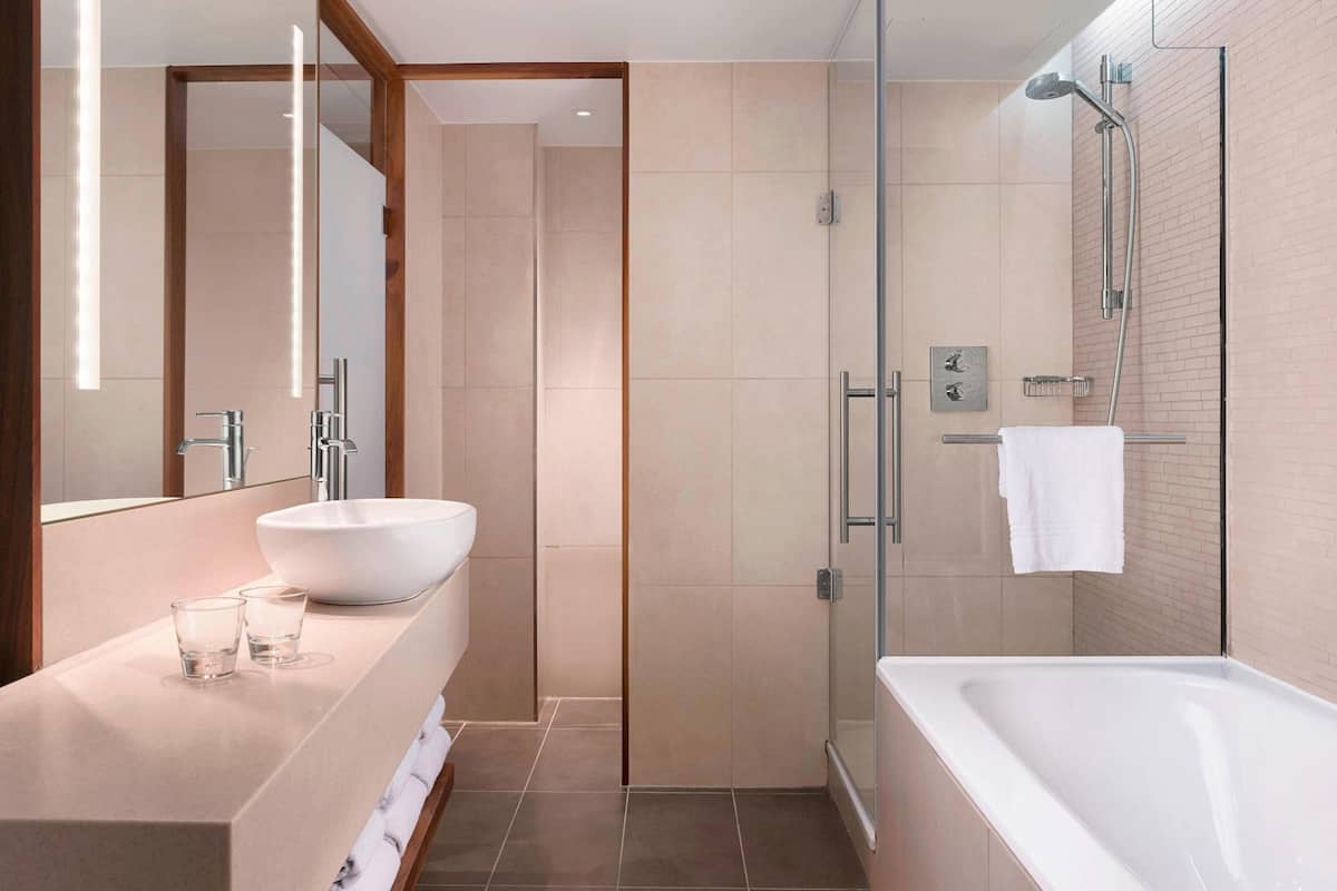 A modern bathroom with a large white sink, a glass shower enclosure, and a bathtub.